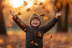 Happy child boy throw up the autumn leaves in the park, a Photo by AlyaAnd