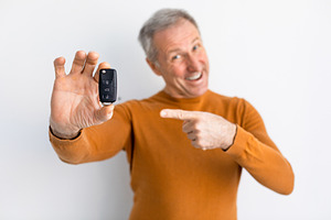 Excited Man Holding Car Key And Pointing, White Background, a Photo by Prostock-Studio