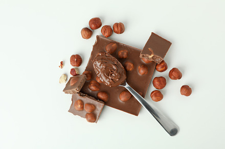 Spoon with chocolate paste and chocolate with nuts on white back, a Food & Drink Photo by AtlasStudio PRO