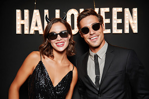 Stylish couple celebrating Halloween in fun costumes at a festive event, a Photo by AlyaAnd