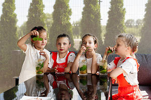 Group of happy children enjoying fresh drinks in a garden setting, a Photo by AS photostudio