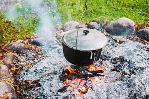 Metal pot over a campfire outdoors, a Food & Drink Photo by BOOCYS