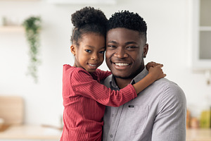 Portrait of cheerful black father and daughter smiling at camera, a Photo by Prostock-Studio