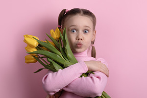 Young girl hugging bouquet of yellow tulips against pastel pink, a Nature Photo by Ales Munt