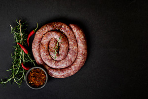 Raw beef sausages on a castiron pan  selective focus containing heap
