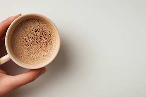 Hand holding a cup of frothy coffee, a Food & Drink Photo by MistyDay