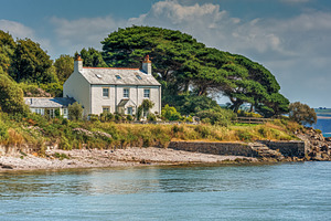 Coastal white house nestled on a green hillside with lush trees,, a Photo by Studio ANNA