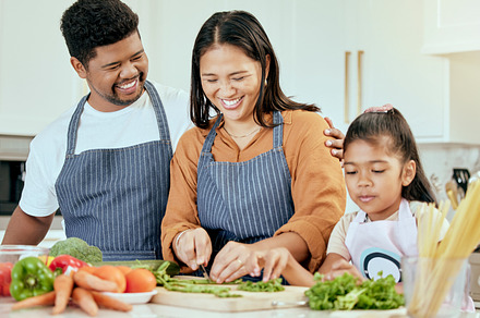 Family, food and cooking in kitchen for health, wellness and nutrition with vegetables and happy people. Happy family, girl and parents bonding while preparing a balanced meal in their home together, a Photo by Peopleimages.com