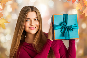 Woman smiling, presenting a beautifully wrapped teal gift box. A, a Person Photo by Studio ANNA