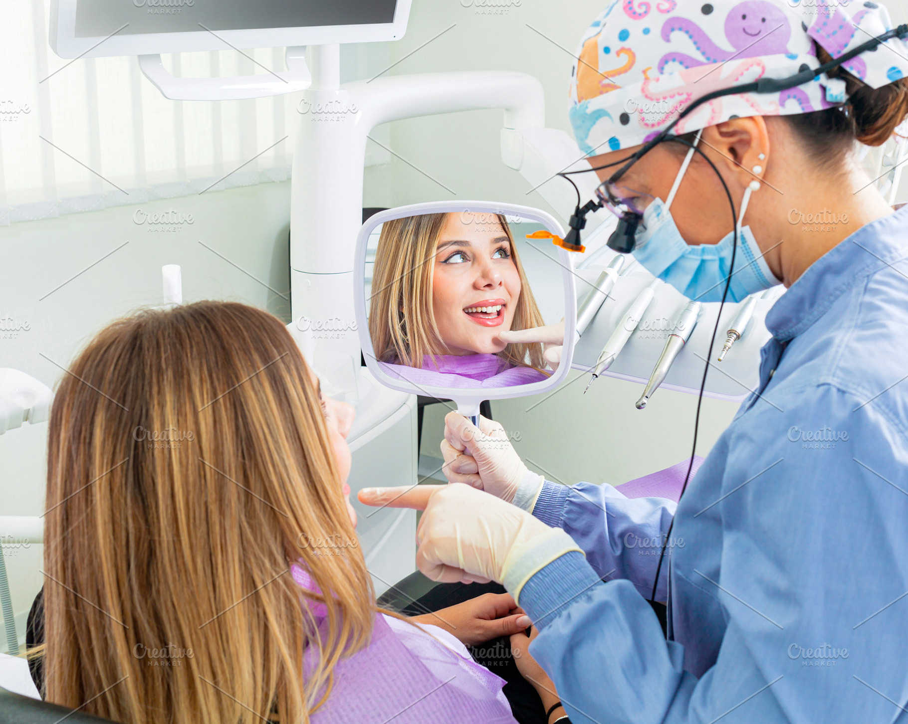 Dentist showing teeth to patient with mirror in dental clinic, a Health & Medical Photo by Antonio Gravante Market