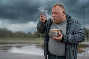 Afult man eating hot food outdoors, a Person Photo by DanFLCreativo