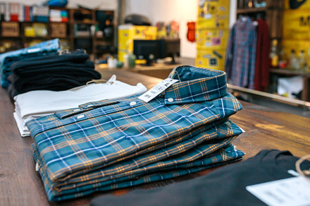 Organized blue plaid shirt stack over counter on vintage clothes shop, a Background Photo by davidpereiras