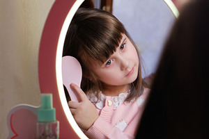 Little girl brushing her hair looking in a toy mirror with LED lights., a Person Photo by Rohan Photography