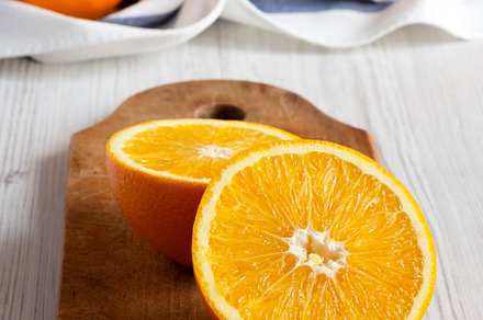 Halved oranges on a rustic wooden board, side view. Close-up., a Food & Drink Photo by LiudmylaChuhunova