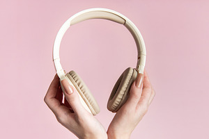 Woman holding wireless headphones on pink background, a Technology Photo by Olena Rudo
