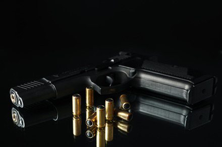Pistol and bullets on mirror table against black background, an Industrial Photo by AtlasStudio PRO