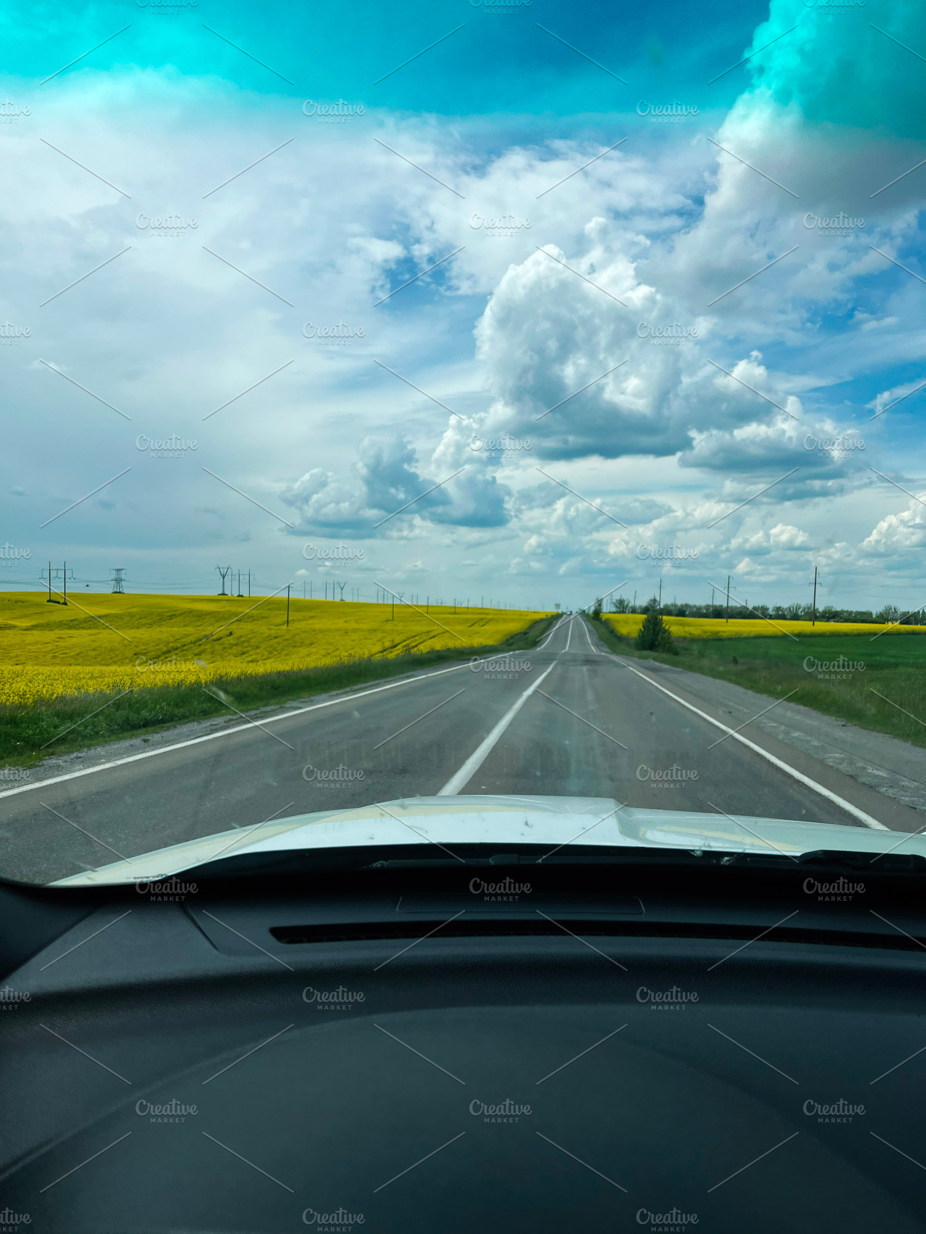 Country road view with a car dashboard foreground and scenic cloudy sky, a Photo by AS photostudio