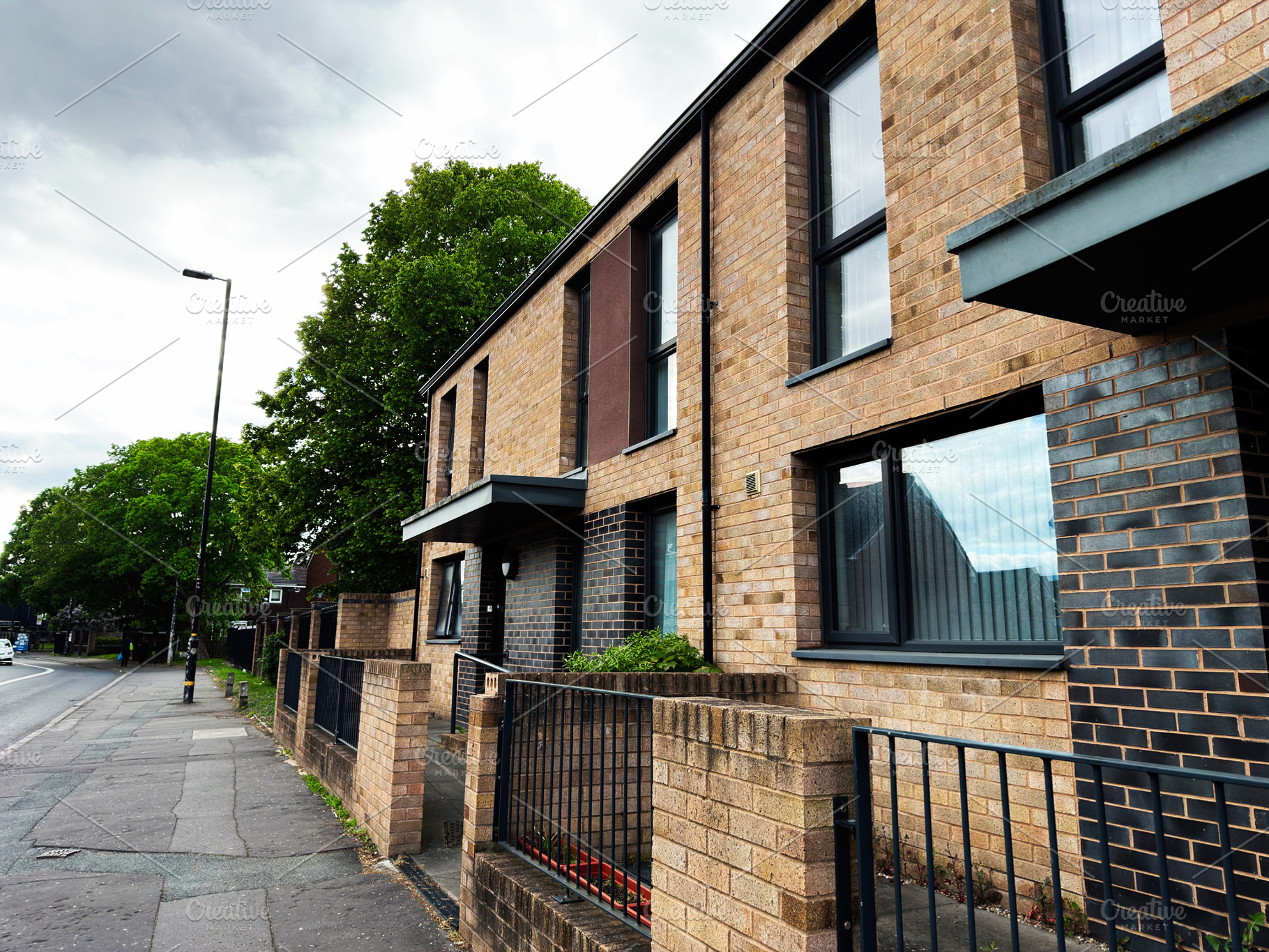 Modern brick apartment building and residential street with tree, a Photo by AS photostudio