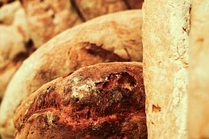 Freshly baked loaves of bread resting on a wooden shelf in a bakery, an Abstract Photo by Antonio Gravante Market