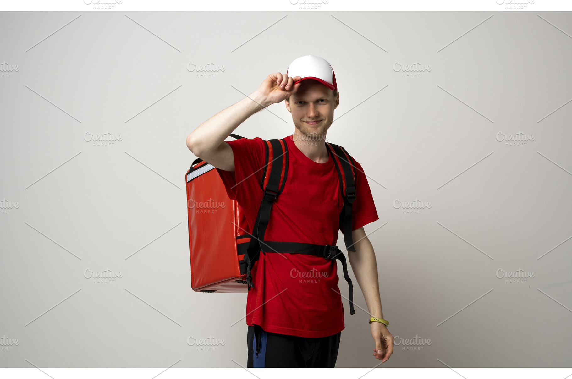 Smiling young delivery man in red, a Person Photo by volodymyrshtun13795