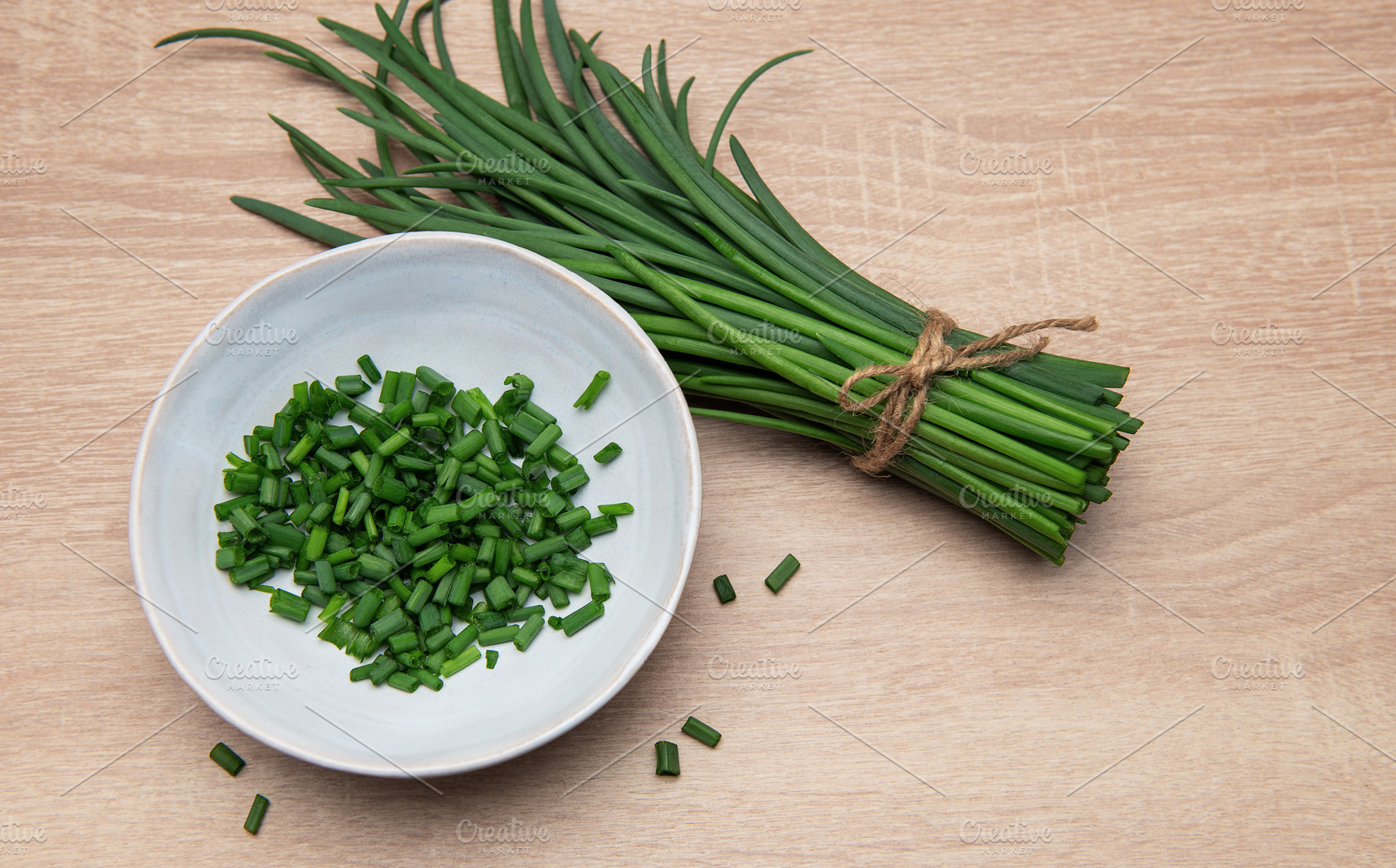 Fresh chives bundle and chopped pieces on wooden surface, a Food & Drink Photo by Olena Rudo