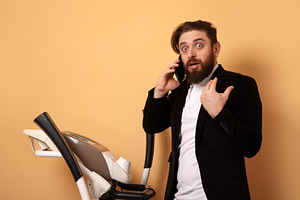 Surprised businessman in suit talking on smartphone next to trea, a Person Photo by Ales Munt