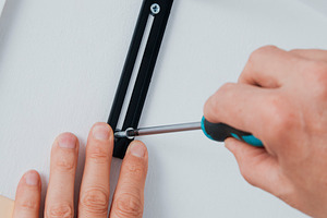 a man fastening a screw in a wall bracket, a Photo by Nito
