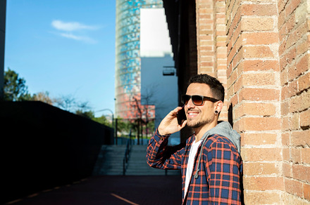 Young man smiling and talking on mobile phone outside, a Person Photo by RF Images