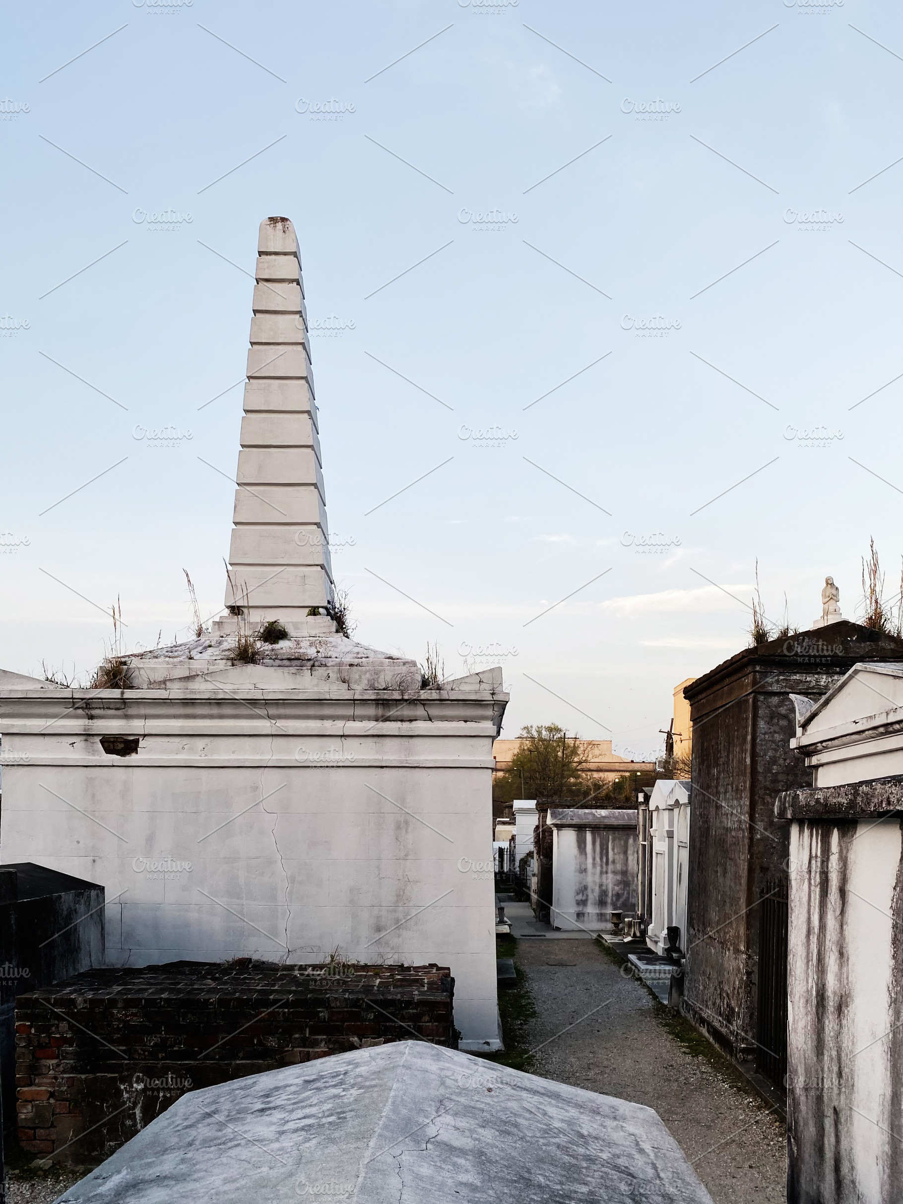 Obelisk tomb in a quiet New Orleans cemetery under a clear blue sky, a Photo by AS photostudio