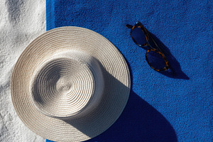 Blue beach towel with sunglasses, a Photo by Virgo Studio
