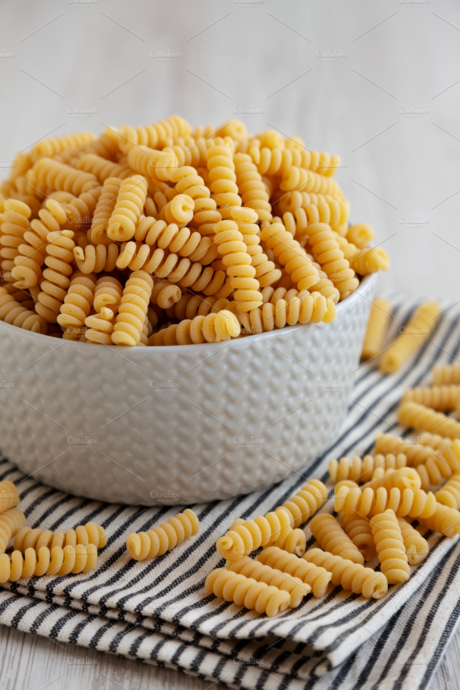Uncooked Organic Dry Fusilli Pasta in a Bowl, side view., a Food & Drink Photo by LiudmylaChuhunova