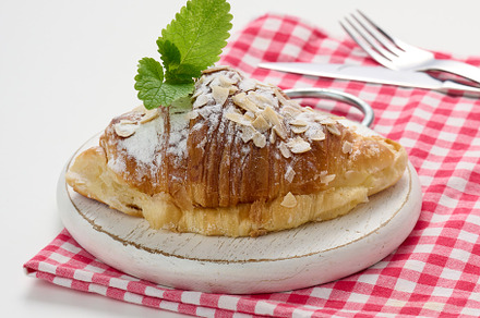 Baked croissant sprinkled with sugar on wooden board, red napkin, a Food & Drink Photo by ndanko