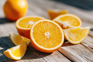 Freshly cut oranges on wooden surface, a Food & Drink Photo by AlyaAnd