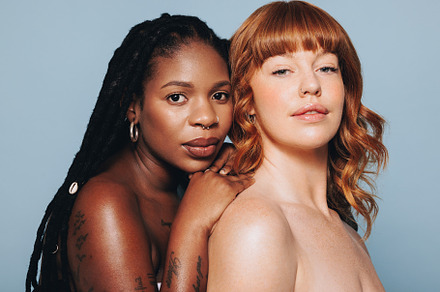 Two young women with different skin tones looking at the camera