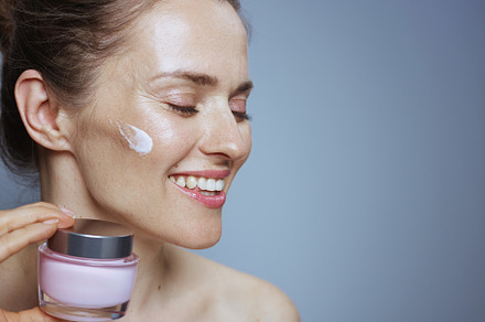 smiling young woman with cosmetic cream jar, a Photo by Alliance Images