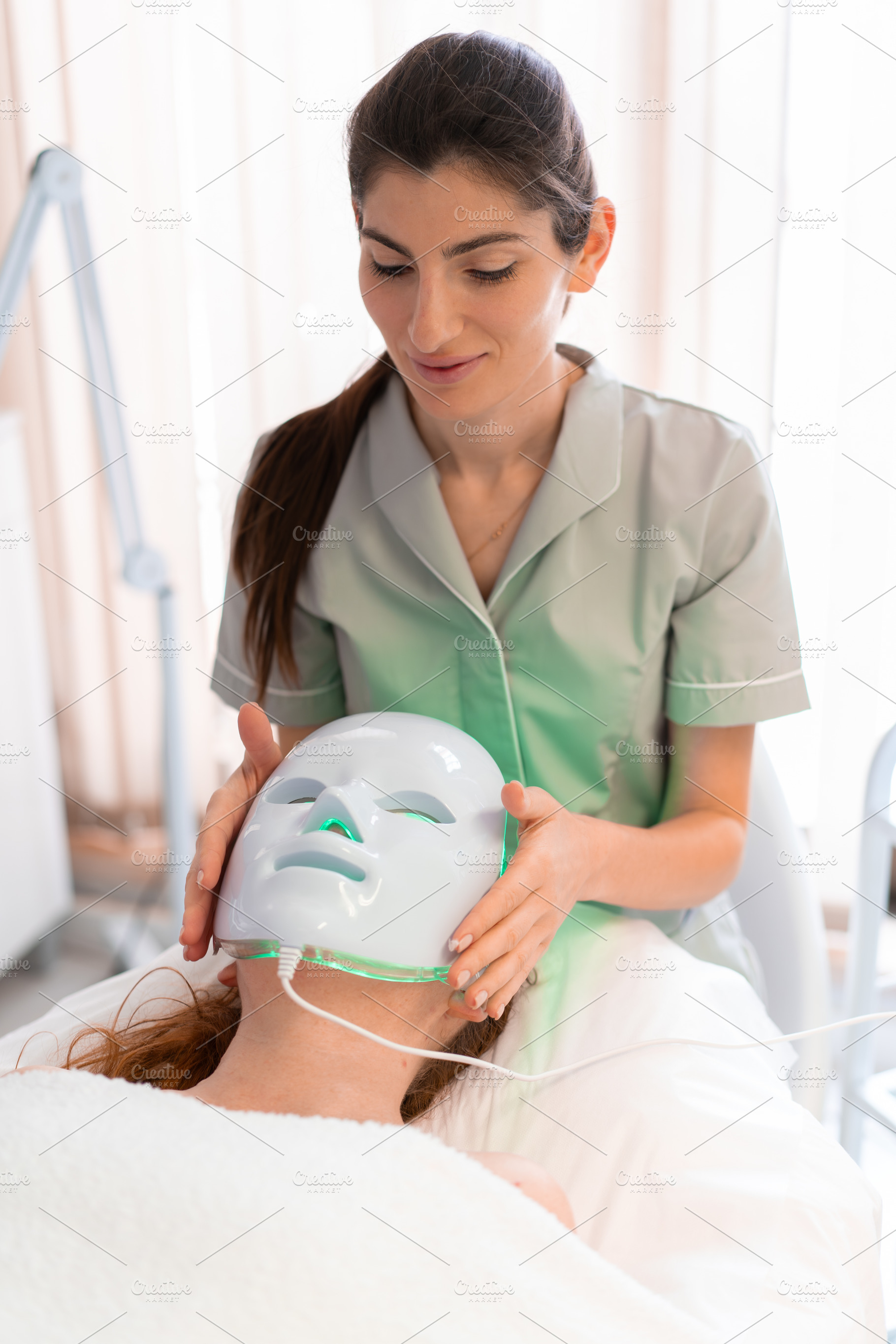 Cosmetologist using modern hydrafacial mask on female client in clinic, a Person Photo by andreonegin market