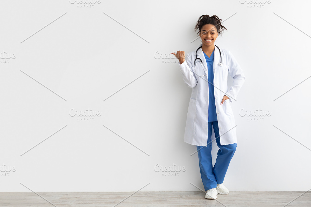 Cheerful female black doctor smiling pointing at copy space, a Photo by Prostock-Studio (Photo 2 of 2)