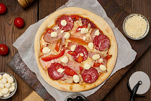Delicious pizza with salami, ham and mozzarella cheese on parchm, a Food & Drink Photo by ndanko