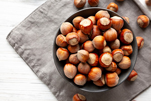 Organic Raw Hazelnuts in a Bowl, top view. Space for text., a Food & Drink Photo by LiudmylaChuhunova