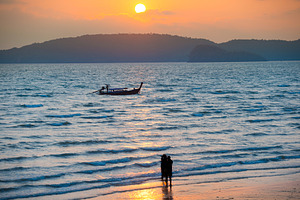Silhouettes of people on beach at sunset, a Nature Photo by Vapi