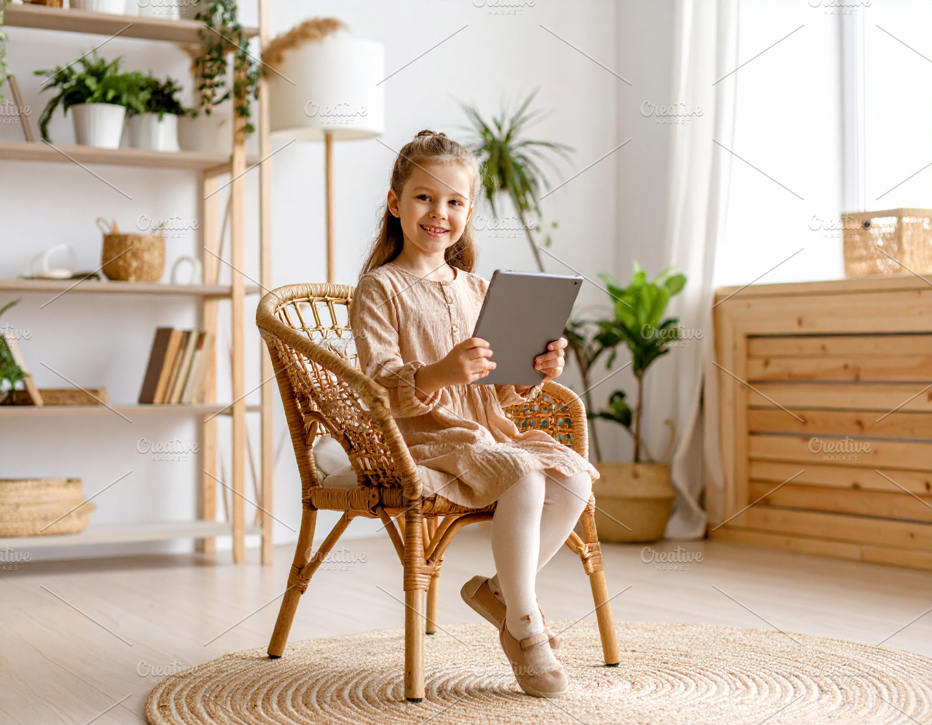 Girl with a tablet sitting on chair at living room while smiling, a Person Photo by DanFLCreativo