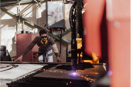 Man working on laser cutter of metal, an Industrial Photo by HalfPoint