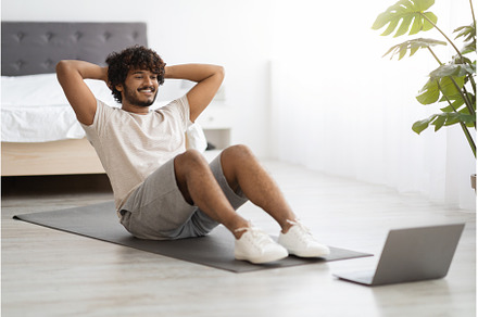Active hindu guy exercising at home, a Sports & Recreation Photo by Prostock-Studio