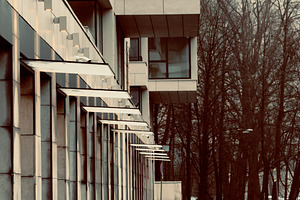 A modern building with large windows and a reflective wet sidewalk, surrounded, an Industrial Photo by Textures & Backgrounds