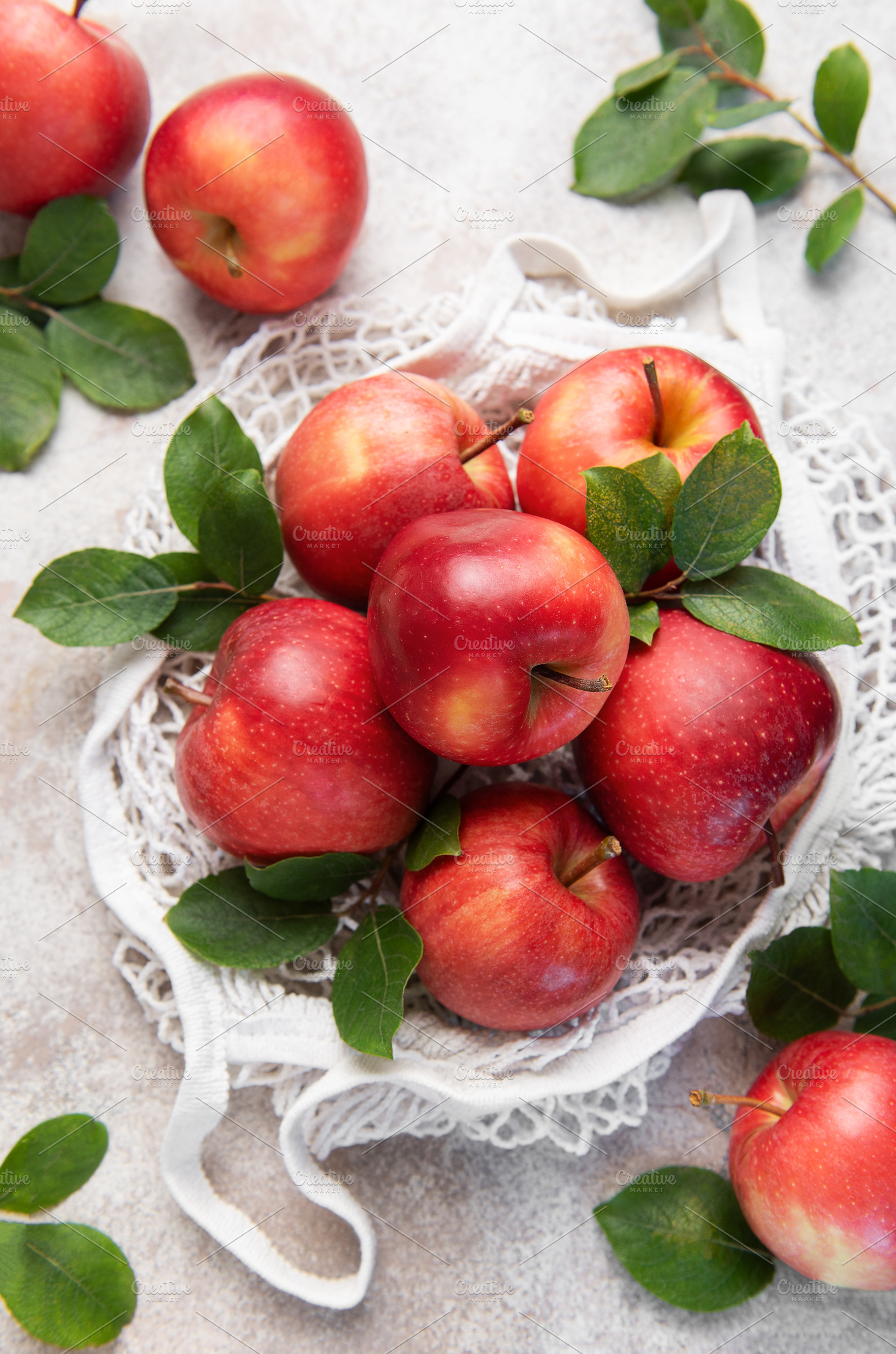 Fresh red apples with leaves in reusable shopping bag on table, a Food & Drink Photo by Olena Rudo