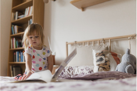 Cute little girl reading book lying, a School & Education Photo by HalfPoint