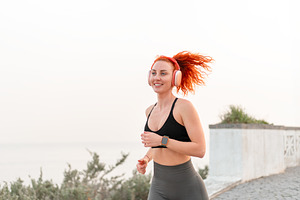 Happy sporty jogger woman jogging against seascape against clear sky, a Person Photo by andreonegin market