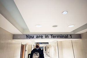 Traveler walks through a bright Manchester airport corridor beneath the You are, a Photo by AS photostudio