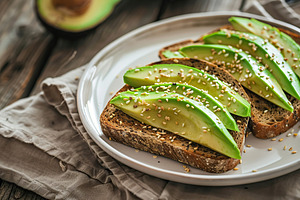 Toasted rye bread with sliced avocado and herbs in plate on wooden table, a Food & Drink Photo by AlyaAnd