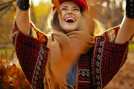 smiling young woman in red hat throwing autumn leafs, a Person Photo by Alliance Images